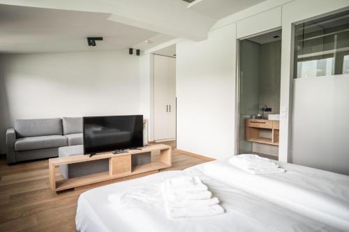 a bedroom with a bed and a tv and a couch at Seehotel Bellevue by keyone in Zell am See