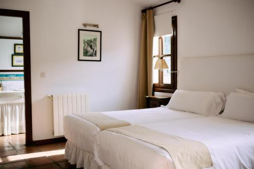a bedroom with a large white bed and a window at Molino Del Santo in Benaoján