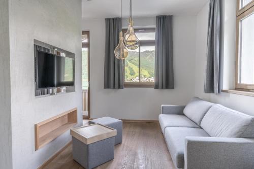 a living room with a couch and a tv at Seehotel Bellevue by keyone in Zell am See