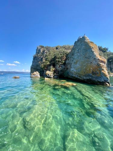 a large rock in the water next to a beach at Agriturismo Arlena in Bolsena