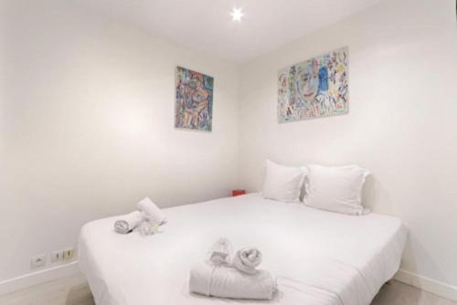 une chambre avec un lit blanc avec des serviettes dessus dans l'établissement Bastille Republique Charming & Cosy Apartment 1BR, à Paris