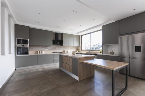 a large kitchen with gray cabinets and a wooden island at Immense appartement 6pièces au Golf in El Mouradia
