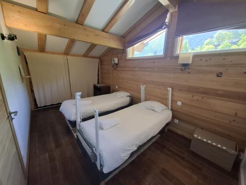 deux lits dans une chambre avec une fenêtre dans l'établissement Chalet du Verney - Pied du Prarion - Sauna, aux Houches