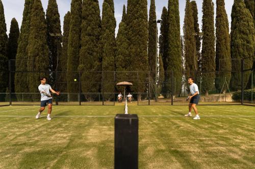two men playing tennis on a tennis court at COMO Castello Del Nero in Tavarnelle in Val di Pesa