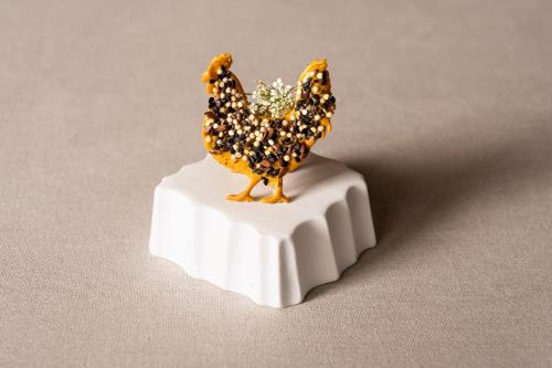 a small figurine of a chicken sitting on a stand at COMO Castello Del Nero in Tavarnelle in Val di Pesa