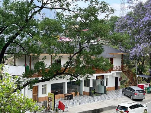 a white house with cars parked in front of it at Sukoon By The Agamya in Pīpalkoti