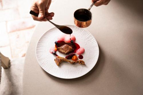 a plate of food on a table with a person holding a spoon at COMO Castello Del Nero in Tavarnelle in Val di Pesa