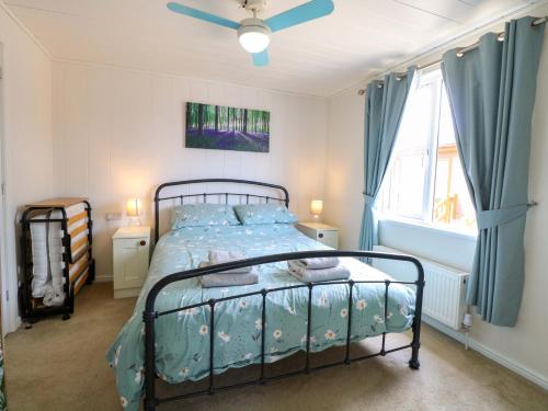 a bedroom with a bed with blue sheets and a window at Oak Tree Holiday Lodge in Stowmarket
