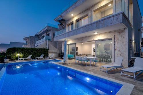 a villa with a swimming pool at night at Olymp Luxury Villa C - Seafront Elegance with Infinity Pool and Exclusive Lifestyle in Kissonerga