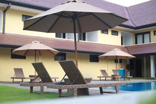 a group of chairs and umbrellas next to a pool at Rajarata Hotel Anuradhapura in Anuradhapura