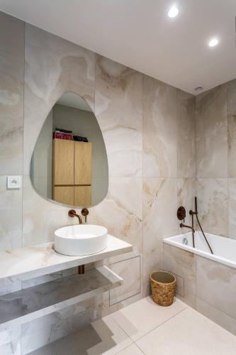 une salle de bain avec un lavabo, une baignoire et un miroir dans l'établissement Très bel Appartement Neuilly, à Neuilly-sur-Seine