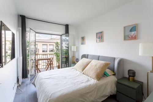 une chambre avec un grand lit et un balcon dans l'établissement Très bel Appartement Neuilly, à Neuilly-sur-Seine