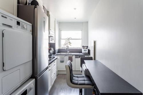 une cuisine avec une table, des chaises et un réfrigérateur dans l'établissement Très bel Appartement Neuilly, à Neuilly-sur-Seine