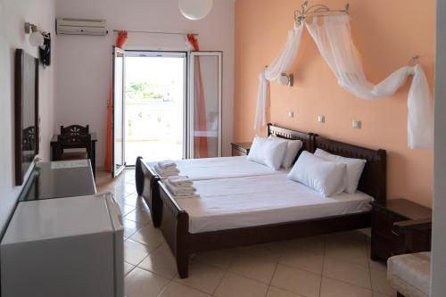 a bedroom with a bed with white sheets and a window at Hotel Alexandros in Ammoudia