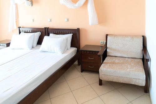 a small bedroom with a bed and a chair at Hotel Alexandros in Ammoudia