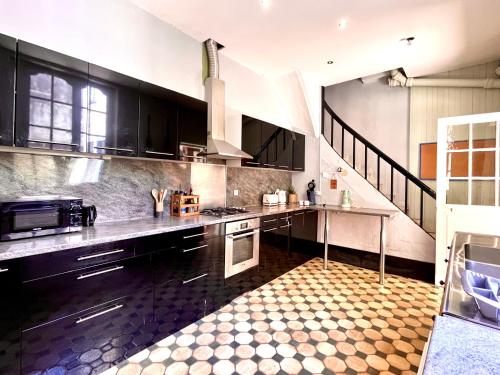 a large kitchen with black cabinets and a staircase at L'imparfait - Maison 5 chambres - Home République in Auxerre