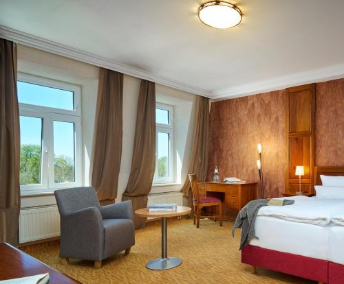 a hotel room with a bed and a chair and a desk at Strand- und Wellnesshotel Preussenhof in Zinnowitz