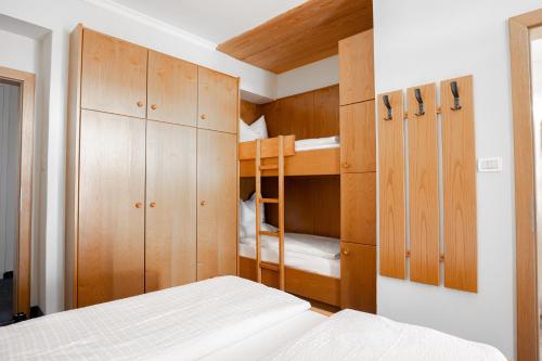 a bedroom with a bunk bed and wooden cabinets at Hotel Euròpa Dolomites in Selva di Val Gardena