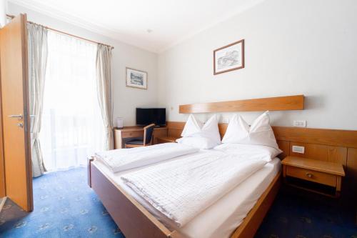 a bedroom with a large bed with white sheets at Hotel Euròpa Dolomites in Selva di Val Gardena
