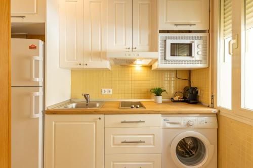 une cuisine blanche avec un évier et une machine à laver dans l'établissement ISG Apartments Estudio en La Alameda, à Séville