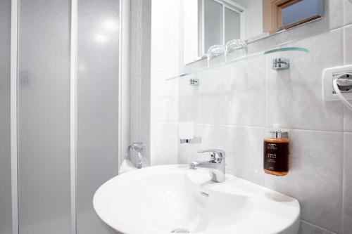 a white bathroom with a sink and a shower at Hotel Euròpa Dolomites in Selva di Val Gardena