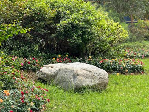 a rock sitting in the grass near some flowers at Yongchun Laimeng Garden Hotel in Yung-ch'un-hsien
