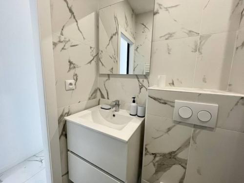 une salle de bain blanche avec un lavabo et un miroir dans l'établissement Nice Signature Andrioli, à Nice