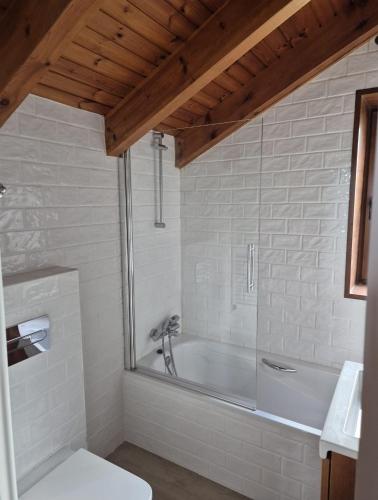 a white bathroom with a tub and a toilet at El Puyal de Benas in Benasque