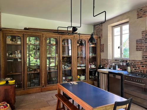 eine Küche mit Holzschränken und einem blauen Tisch in der Unterkunft Les écuries du château in Boissy-Saint-Léger