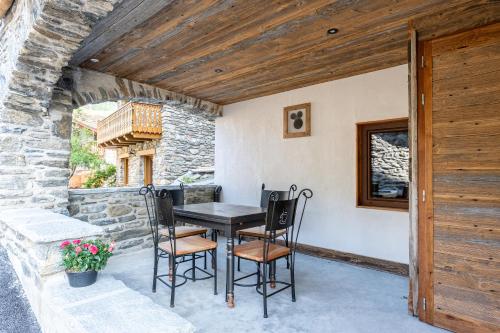 une table et des chaises sur une terrasse avec un mur en pierre dans l'établissement Appartement ô Canton, à Val Cenis