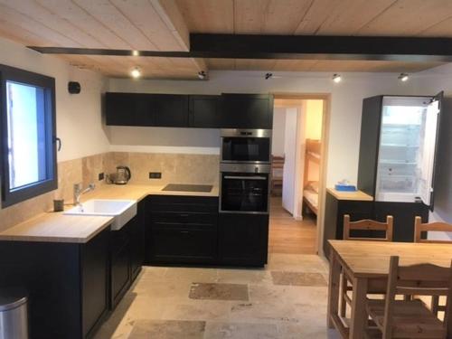 une cuisine avec des armoires noires et une table ainsi qu'une salle à manger dans l'établissement La Pieuca, 50 m2 apartment in old farmhouse, aux Contamines-Montjoie
