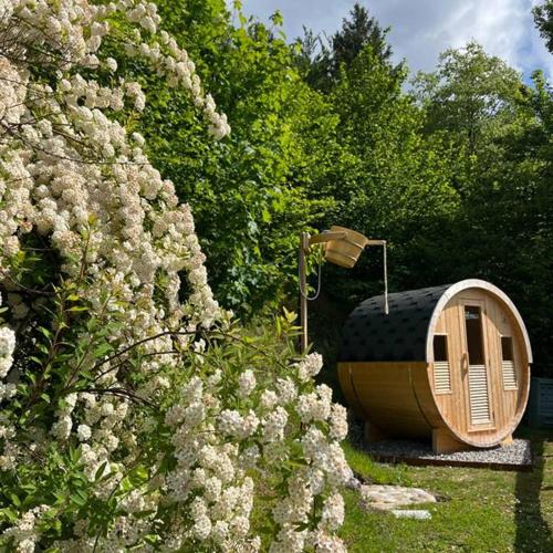 a wooden tub sitting next to a bush with flowers at Chalet Ai Grecc in Mezzolago