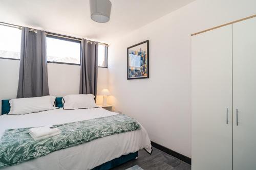 a bedroom with a bed and two windows at Penthouse City Centre Apartment in Royal Tunbridge Wells