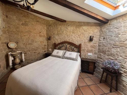 a bedroom with a bed in a stone wall at Casa Labrega da Torre in Silleda