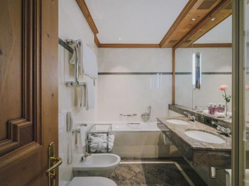 a bathroom with two sinks and a toilet at Kulm Hotel St. Moritz in St. Moritz