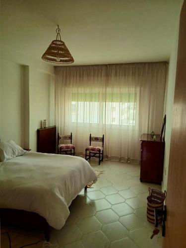 une chambre avec un lit et deux chaises et une fenêtre dans l'établissement Chez Nouzha, à Tanger