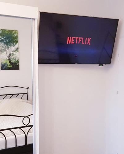 a tv on a wall in a bedroom with a bed at Apartament u Anielki in Uniejow