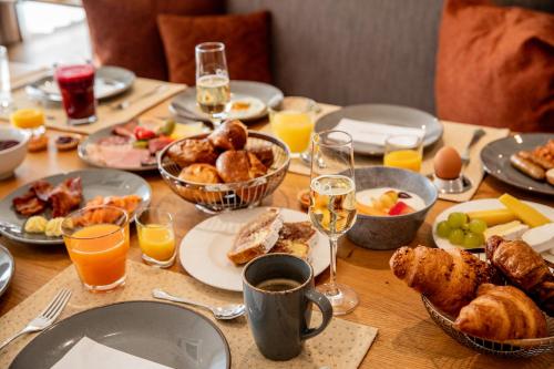 een tafel met ontbijtproducten en een glas sinaasappelsap bij Pfalzblick Wald Spa Resort in Dahn