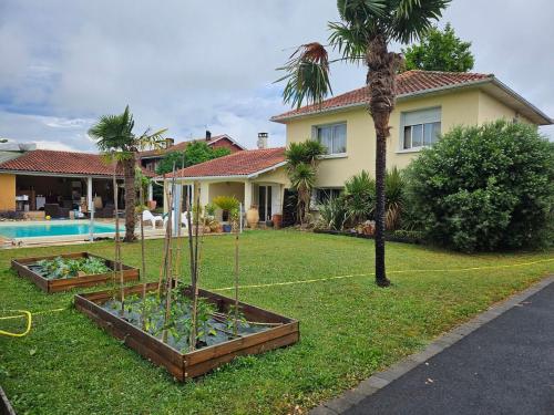 une maison avec une cour ornée d'un palmier dans l'établissement Chambre meublée avec cuisine équipée, à Vic-en-Bigorre
