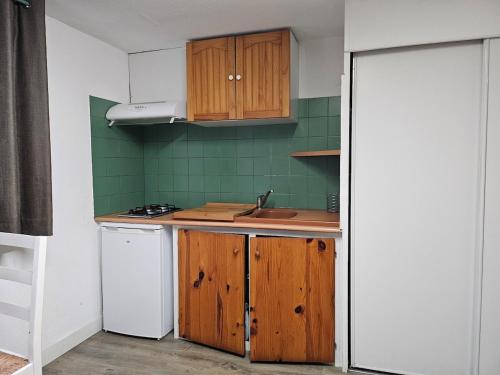 une cuisine avec des armoires en bois et un évier dans l'établissement Chambre meublée avec cuisine équipée, à Vic-en-Bigorre