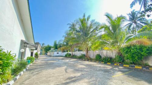 a street with palm trees and a white fence at Allisa Motel in Anyer-Lor