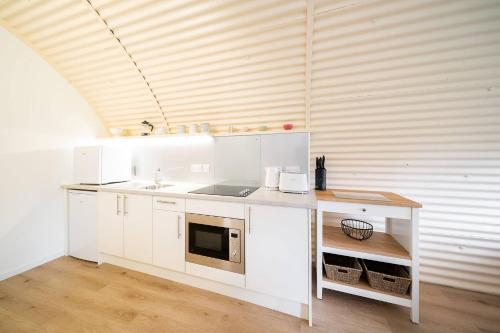 a kitchen with white cabinets and a microwave at Cultybraggan Hut 37 in Comrie