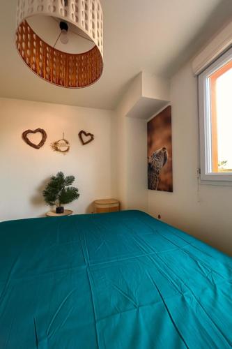 une chambre avec un lit bleu avec une fenêtre dans l'établissement Le jardin des senteurs - 2 pièces avec jardin, à Grasse