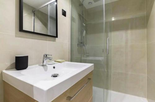 W łazience znajduje się biała umywalka i prysznic. w obiekcie Magnifique Appartement avec Sauna et Jacuzzi w Paryżu