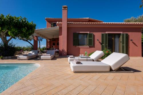 a patio with white chairs and a swimming pool at Artblue Villas in Tsoukaladhes