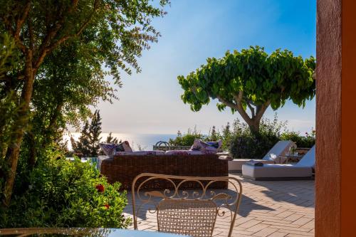 a patio with chairs and trees and the ocean at Artblue Villas in Tsoukaladhes