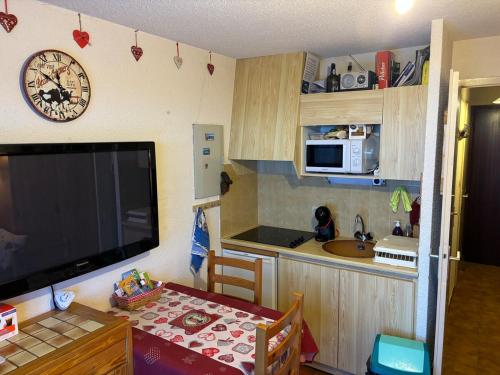 une petite cuisine avec une table et une horloge murale dans l'établissement Le Panoramique I Studio, à Thollon-les-Mémises
