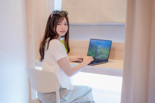 a woman sitting at a desk with a laptop at SNOW HOUSE Buriram in Buriram