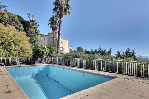 une piscine bleue avec une clôture et des palmiers dans l'établissement Penthouse de charme, à Vallauris