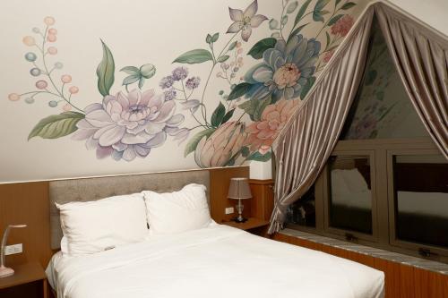 a bedroom with a bed with a flower mural on the wall at Faru Pine Woods Villa in Xuan An